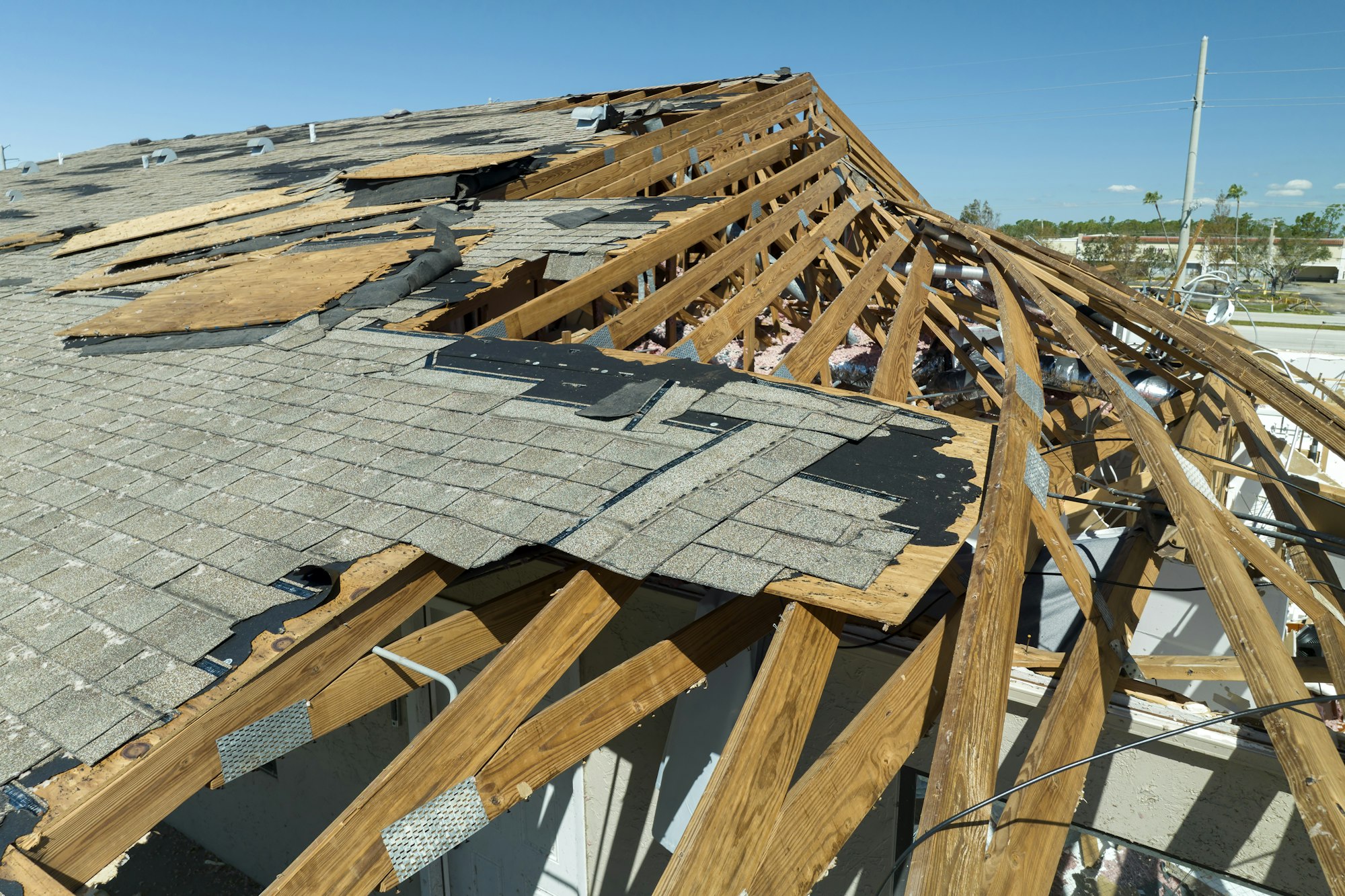 Damaged house roof with missing shingles after hurricane Ian in Florida.